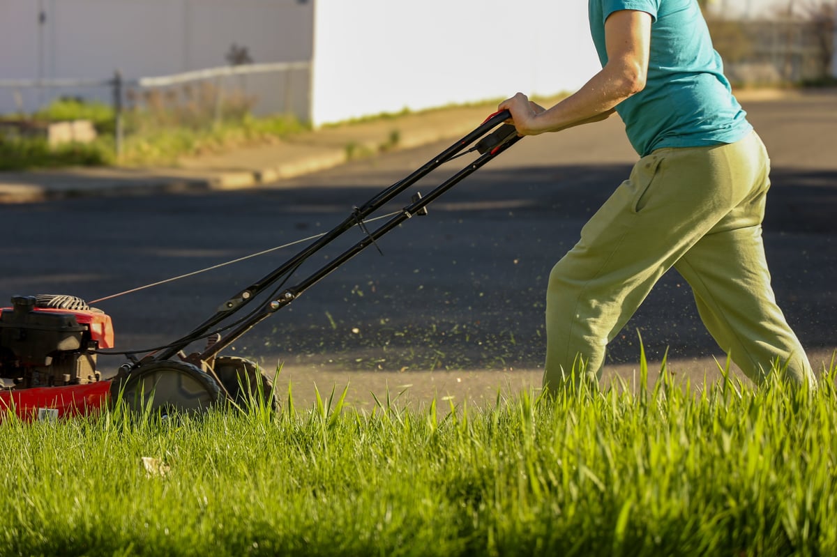Landscaping service worker mowing lawn